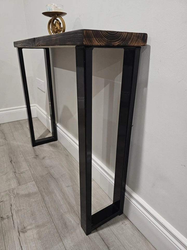 A narrow console table with a dark stained wood top and black metal frame legs