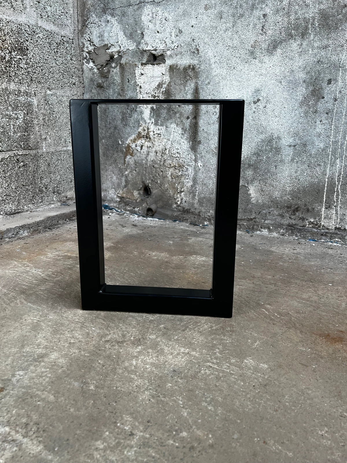 Single black rectangular steel table leg standing upright
