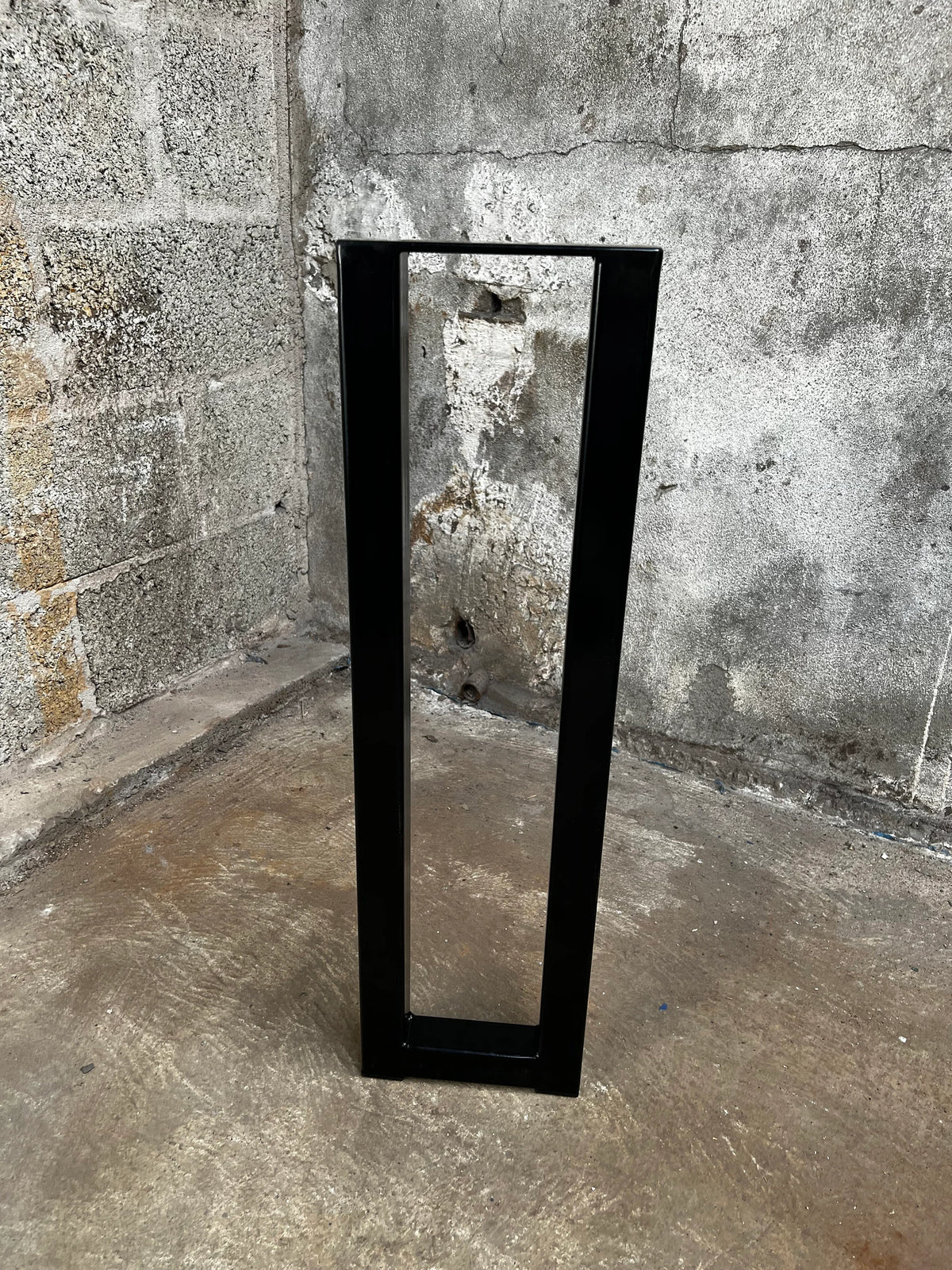Narrow black rectangular steel table leg standing upright